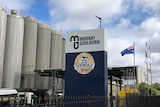 A dairy factory showing metal silos in the background, with a sign in the foreground showing the Devondale Murray Goulburn logos