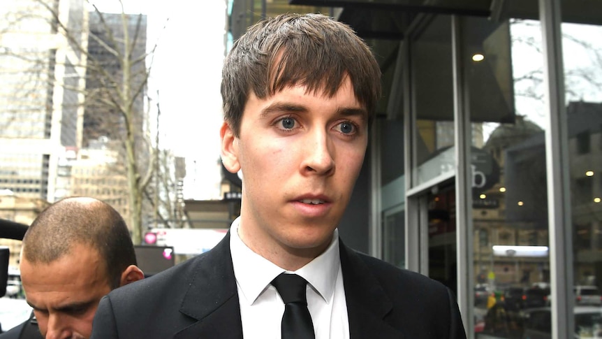 James Haberfield is dressed in a black suit and tie as he walks down a CBD street.