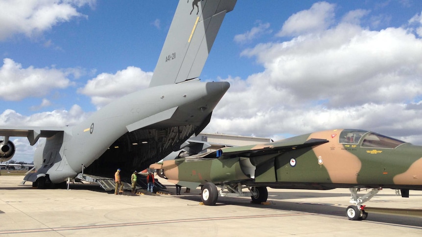 An RAAF F-111 jet is loaded into a C17 cargo plane