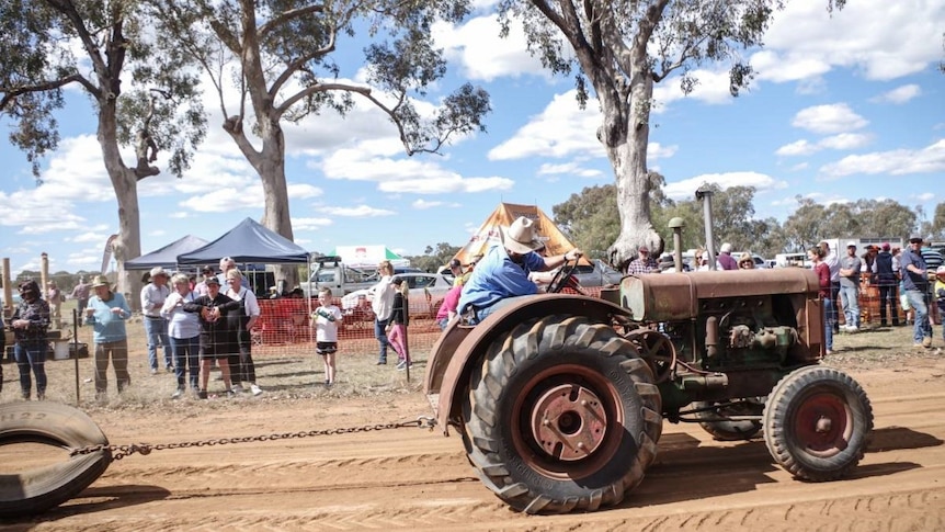 A tractor pulls a tyre while spectators watch on