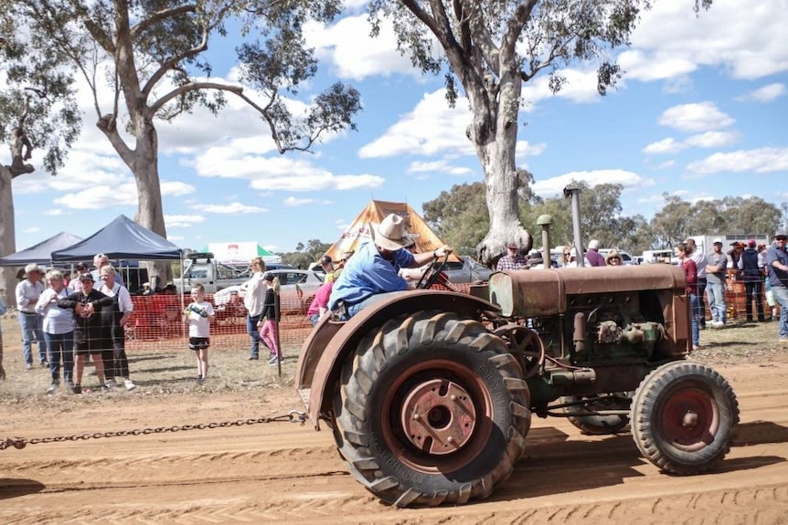 A tractor pulls a tyre while spectators watch on