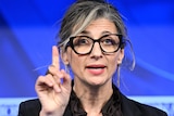  Francesca Albanese holds one finger up while addressing the National Press Club