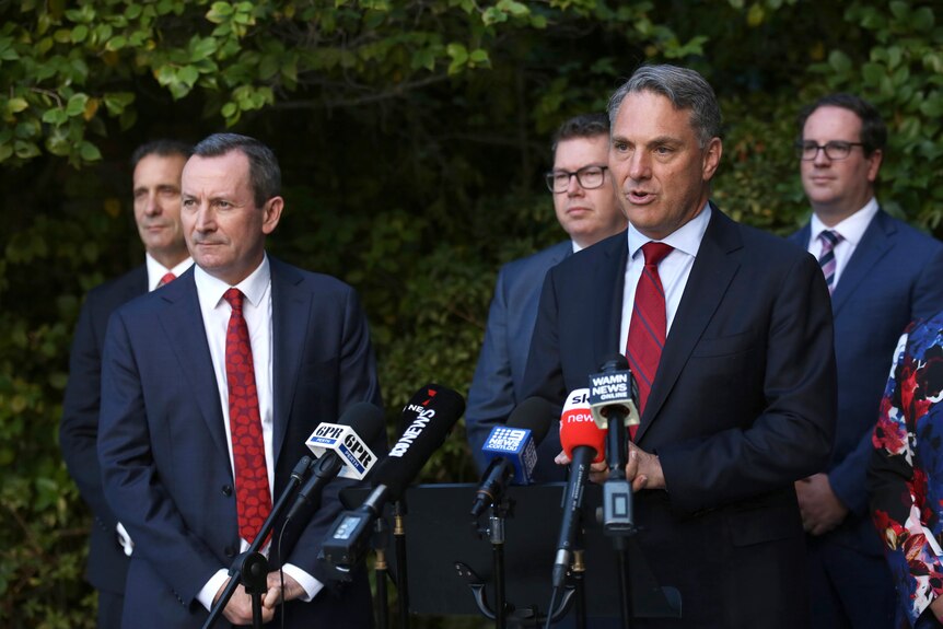 A wide shot of Richard Marles talking during a media conference outside, with Mark McGowan and others alongside him.