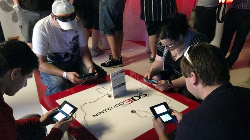 A group of gamers test out games on the Nintendo 3DS at EB Expo