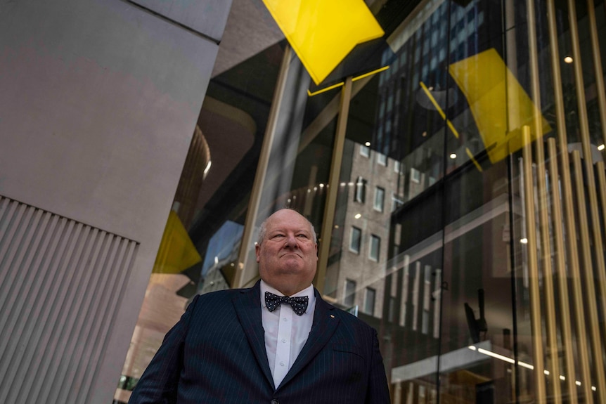 a man stands under a yellow bank logo