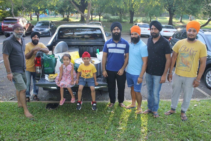 Several members of Darwin's Sikh community handing out food.