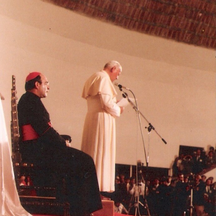 A printed portrait photo shows a red church altar with the Pope speaking in white vestments beside a cardinal.