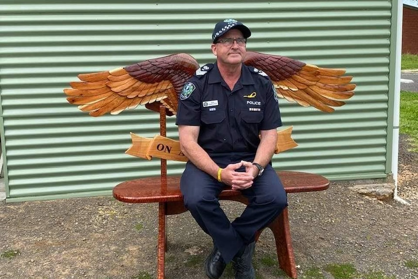 Man sits on bench with angel wings
