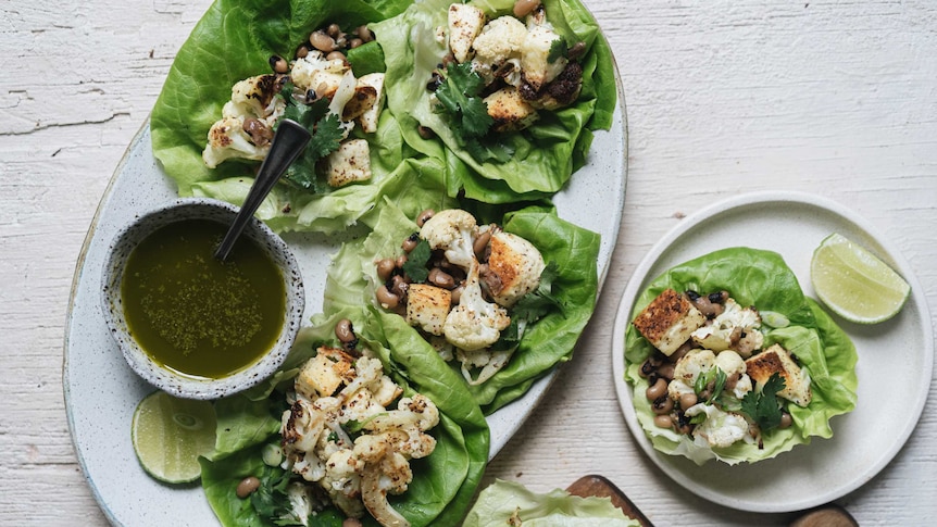 Roast cauliflower and paneer san choy bow served with lime wedges and coriander chilli oil, a healthy dinner.