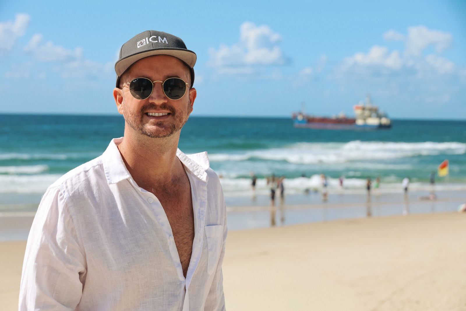 Hombre de pie en la playa con una excavadora al fondo