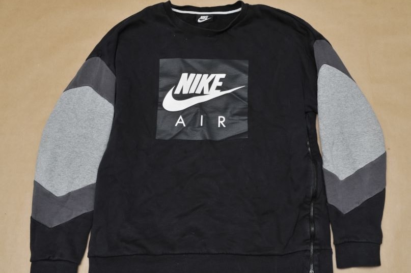 A black and grey jumper with a Nike logo and the words "Nike Air" printed ont eh front. A zip runs down one side.