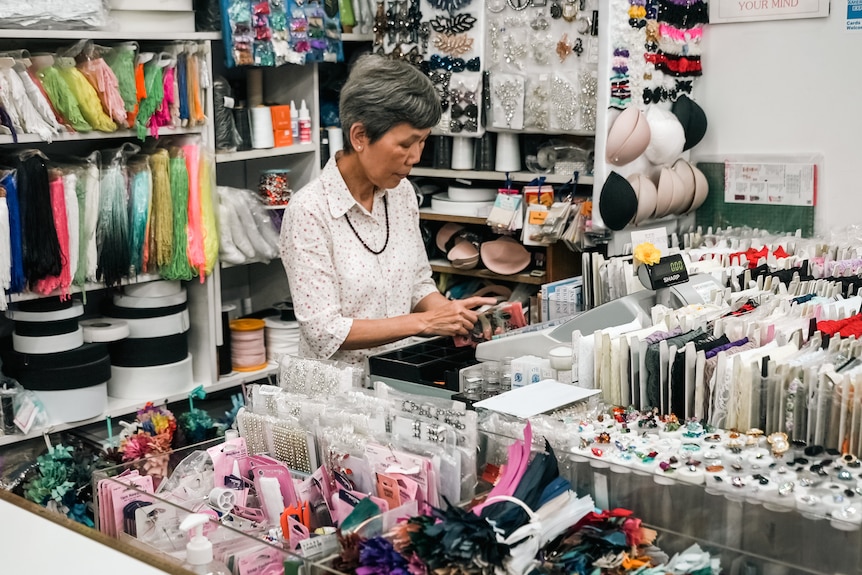 a woman in a material shop putting money in a cash register