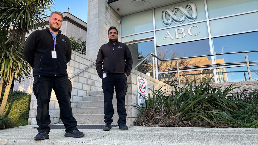 Two parking inspectors stand out the front of an office smiling