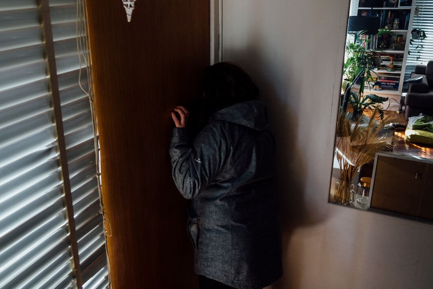 A woman standing by a door inside a house.