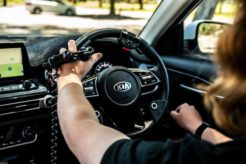 Max Devery's holds with steering wheel while wearing specialised hand controls.