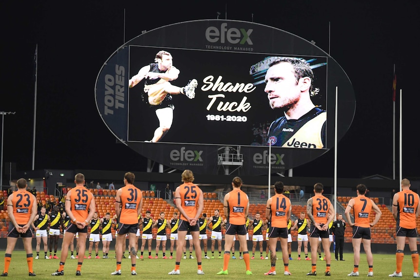GWS and Richmond AFL players stand in formation as they observe a minute's silence in memory of Shane Tuck.