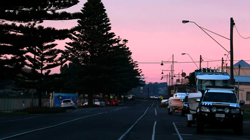 Portland's ocean boulevard during pink sunrise with boats parked along street