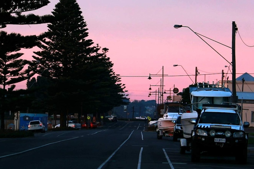 Portland's ocean boulevard during pink sunrise with boats parked along street