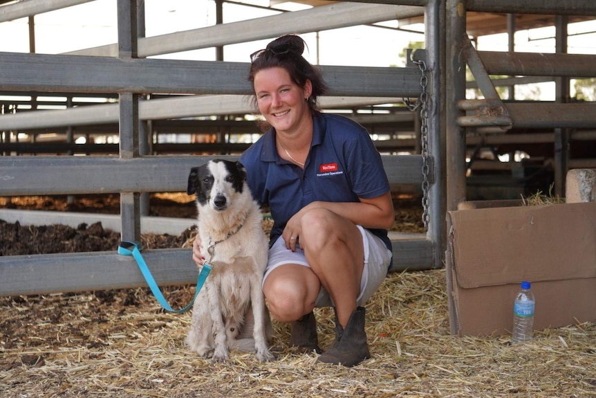 Chloe Thyne pictured crouching in a horse stall with her dog.