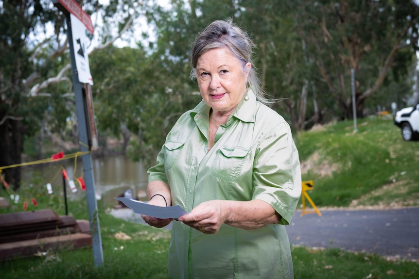 A woman standing next to a river with a bill