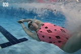 a female swimmer underwater in pink and black simmers pushing off the wall