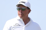 Wearing sunglasses and a hat, Phil Mickelson surveys the fairway