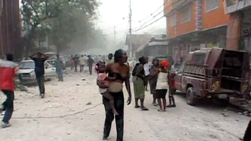 A woman walks through the streets with a baby after the 7.0 magnitude earthquake