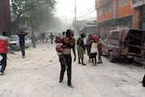 A woman walks through the streets with a baby after the 7.0 magnitude earthquake