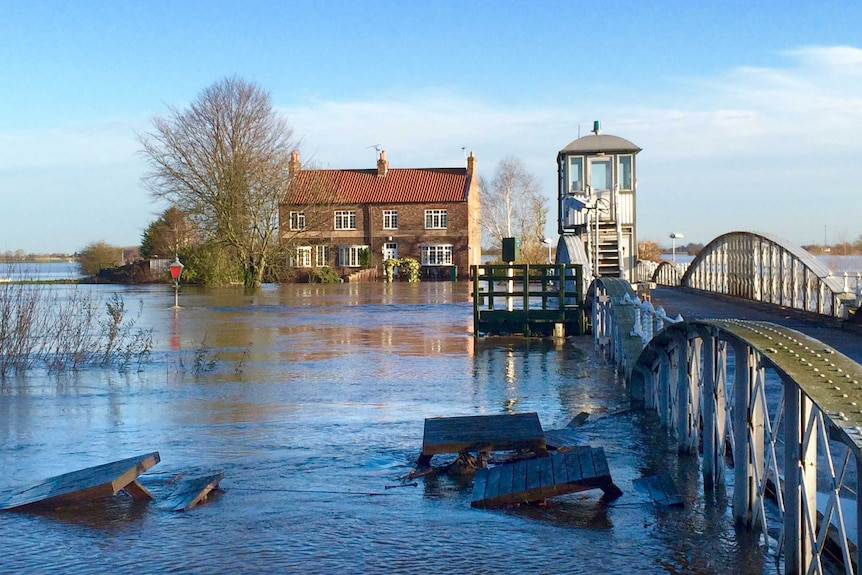 Floodwaters laps at the underside of a bridge and covers the land to the horizon.