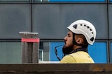 A construction worker in a hardhat poking his head above a barrier