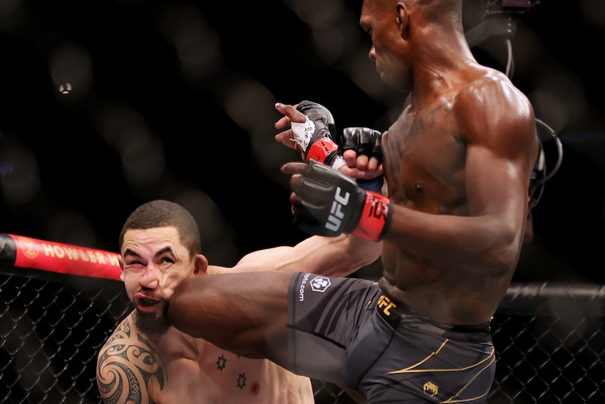 Israel Adesanya knees Robert Whittaker in the face. 