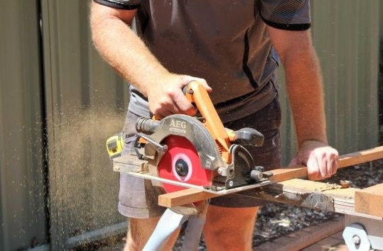 An unidentified tradie cuts a piece of wood.