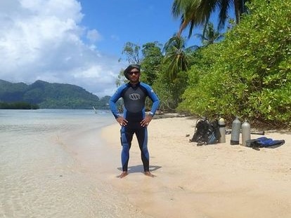 Man in wet suit stands on beach