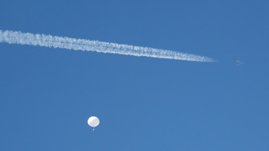 a jet flies in the sky past the Chinese spy balloon off the coast of South Carolina