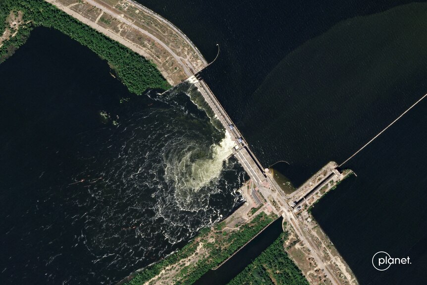 An aerial shot shows a small amount of water being released from the dam. 