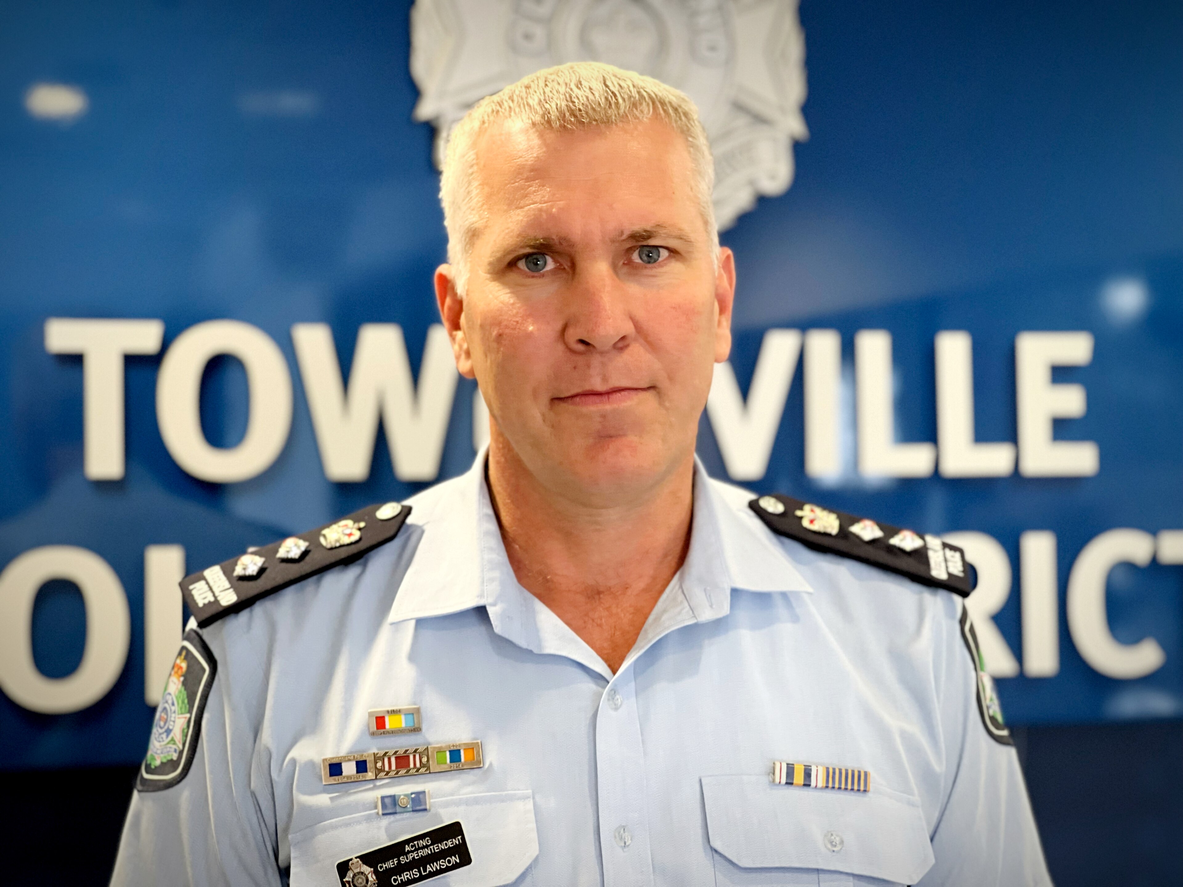 A police officer in uniform stands in front of police signage