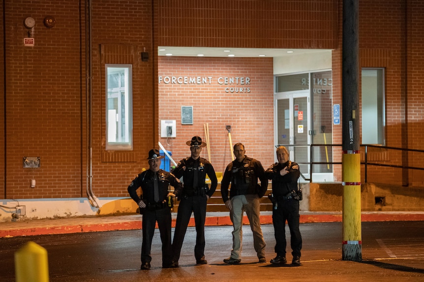 Four policemen stand outside a station
