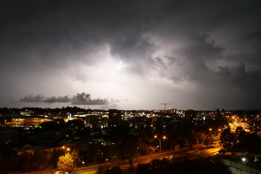 A bright lightning strike over a city at night.