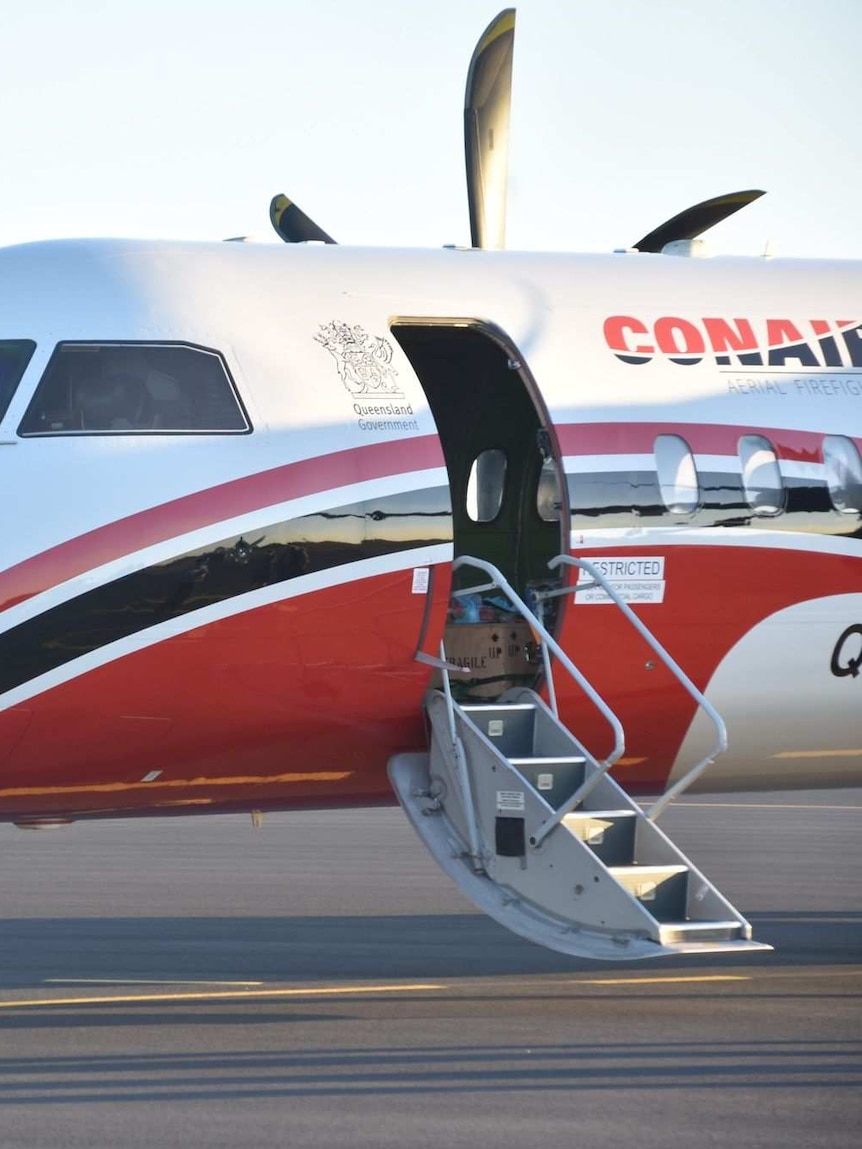 The nose of a plane on the tarmac. It is painted red and white.