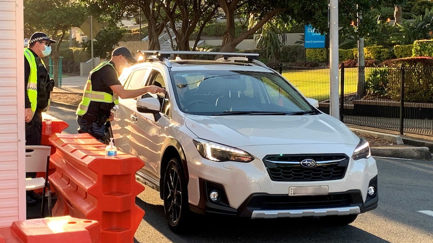 Police officers perform checks as car crosses newly reopened Queensland-NSW border bubble 