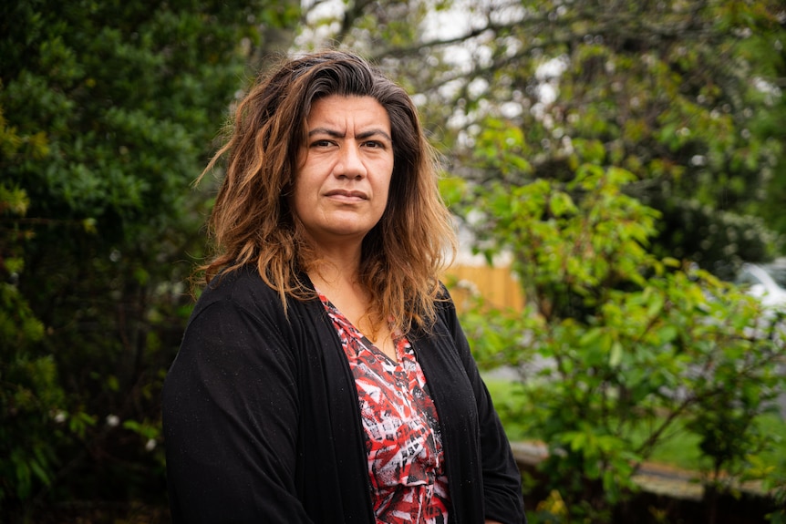 A Samoan woman stands in her garden, looking at the camera. 