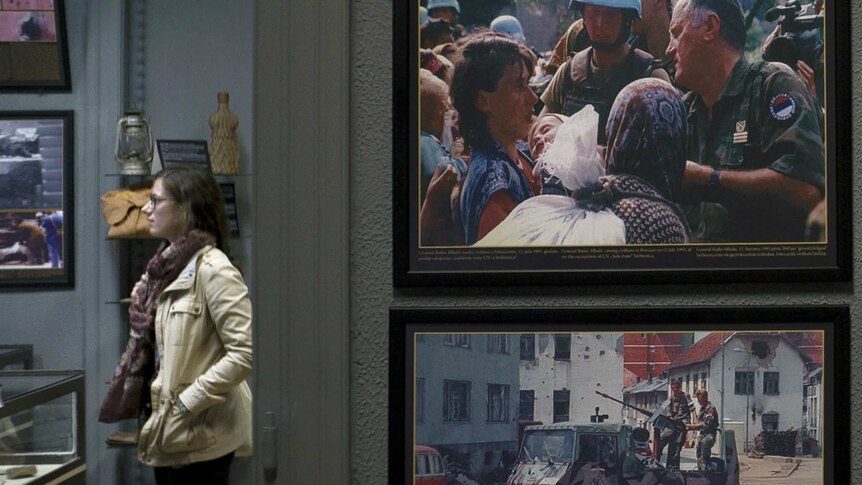 Tourist Fanny Verkmijlen in Sarajevo, with images of the Srebrenica massacre in foreground.