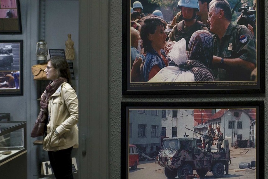 Tourist Fanny Verkmijlen in Sarajevo, with images of the Srebrenica massacre in foreground.