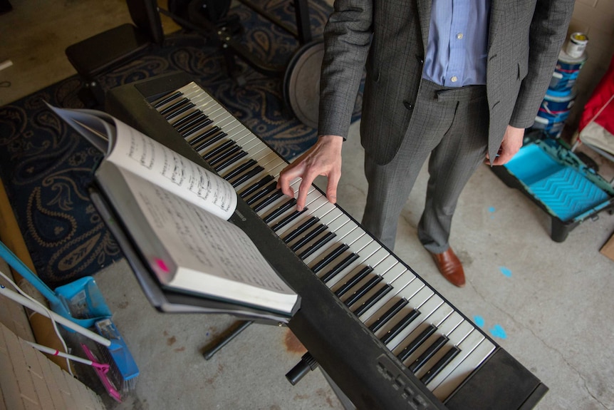 An overhead shot of a man in a suit playing a keyboard in a garage.