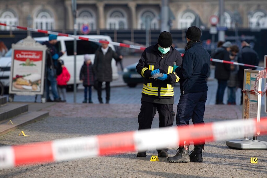 Police officers stand behind a caution tape at the Schinkelwache building in Dresden.