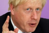 Boris Johnson with mussed blonde hair gestures as he responds to a question