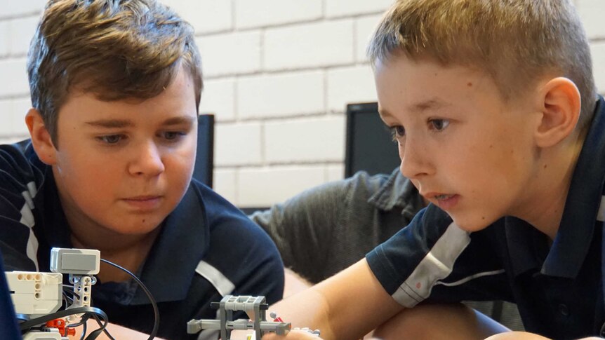 Two school students working with robots.