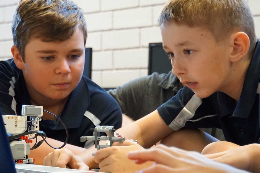 Two school students working with robots.