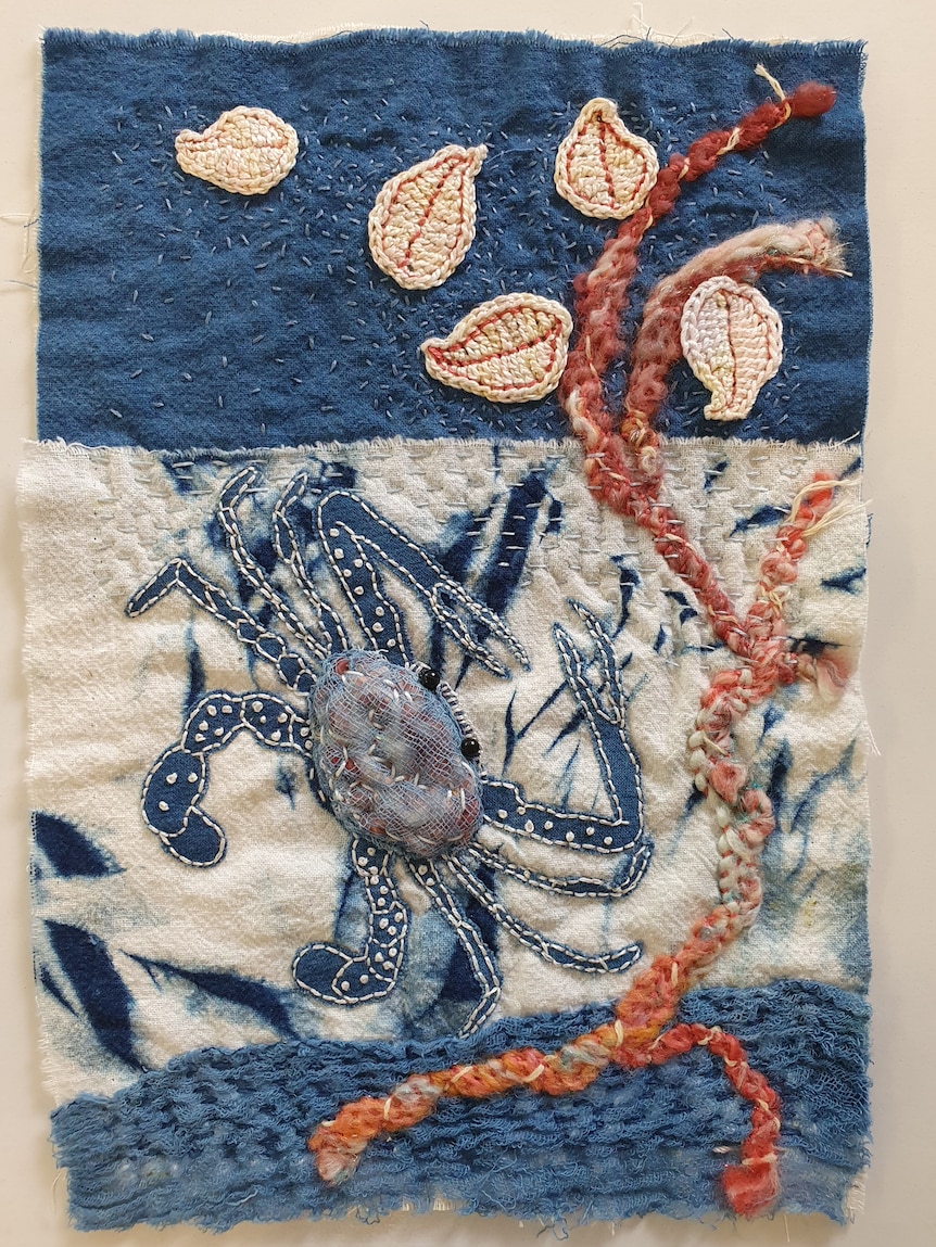A crab stitched into a piece of cloth for a community quilt.