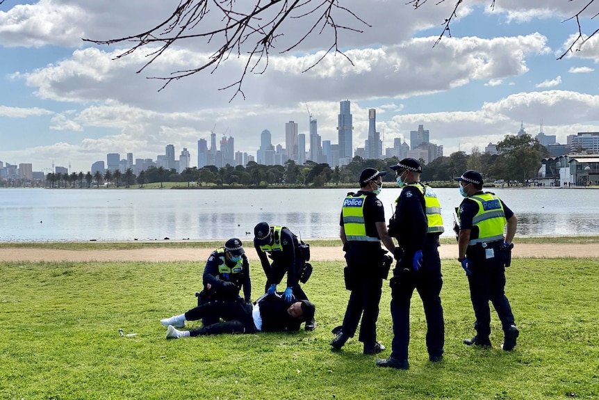 Two police arrest a man on the ground as three other officers look on during an anti-lockdown protest in Melbourne.